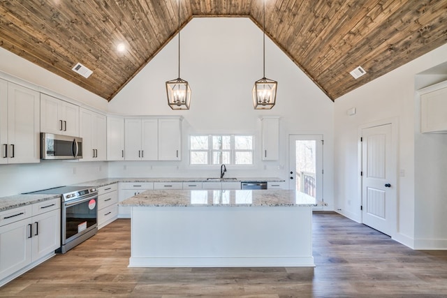 kitchen with high vaulted ceiling, appliances with stainless steel finishes, pendant lighting, and white cabinetry