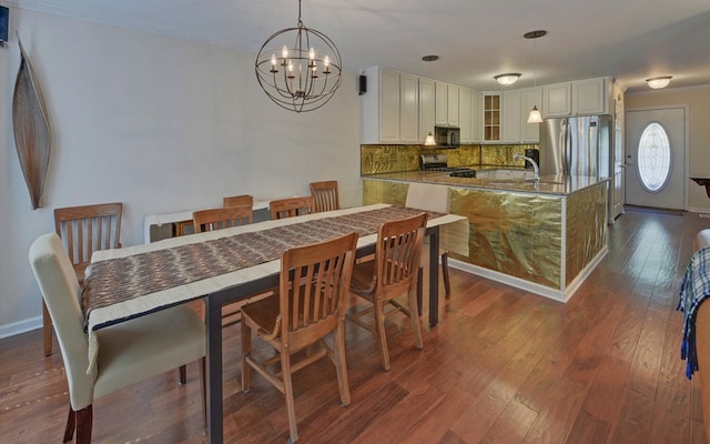 dining area featuring ornamental molding, dark wood-type flooring, and an inviting chandelier