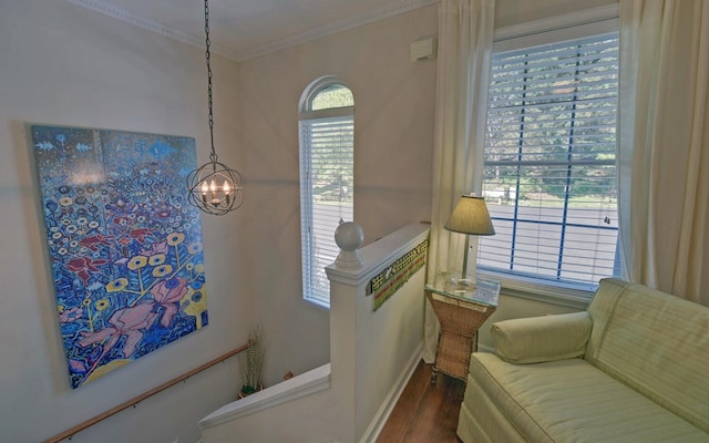 sitting room with hardwood / wood-style flooring, an inviting chandelier, a wealth of natural light, and ornamental molding