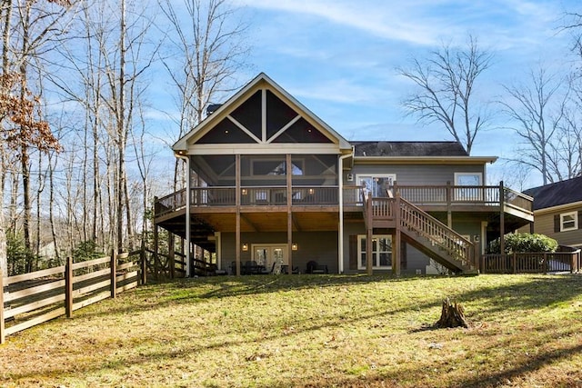 exterior space featuring a sunroom, a deck, and a lawn