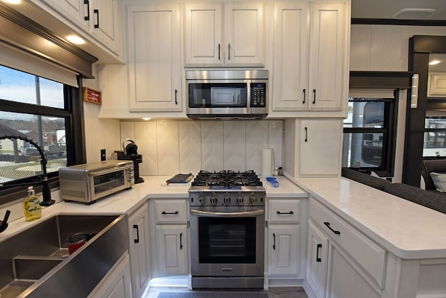 kitchen with backsplash, white cabinets, and stainless steel appliances