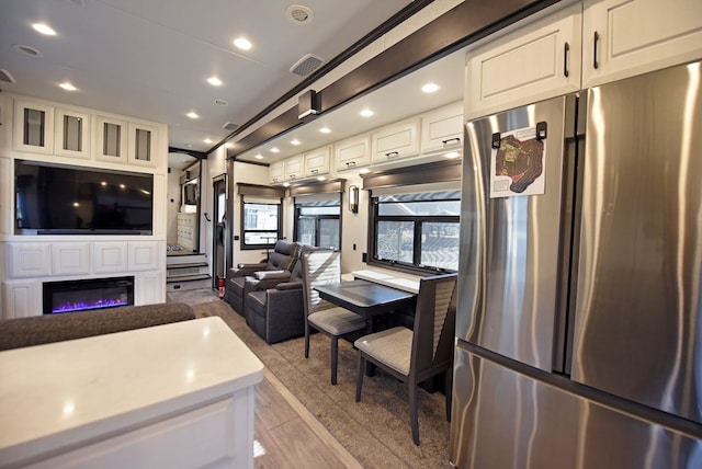 kitchen featuring stainless steel fridge, white cabinetry, and light hardwood / wood-style floors