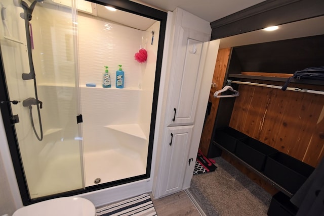 bathroom with a shower with shower door and wood-type flooring