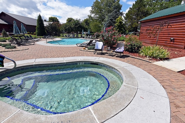 view of swimming pool featuring a patio area and a hot tub