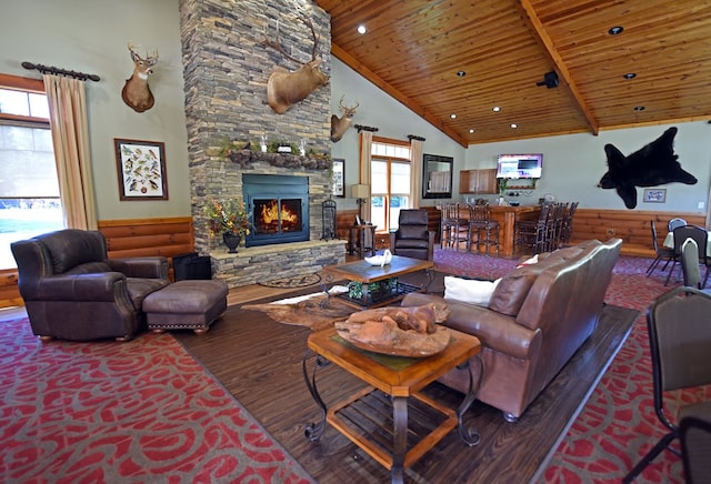 living room with a stone fireplace, wooden ceiling, dark hardwood / wood-style floors, high vaulted ceiling, and rustic walls