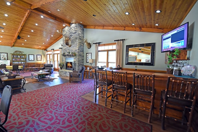 dining room with wood ceiling, a stone fireplace, hardwood / wood-style flooring, high vaulted ceiling, and beam ceiling