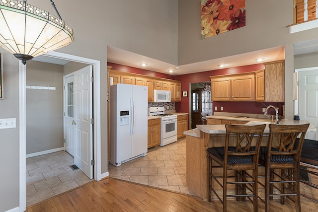 425 Tarheel Dr W, Murphy, NC 28906 - kitchen with white appliances, light wood-style flooring, a peninsula, a towering ceiling, and light countertops