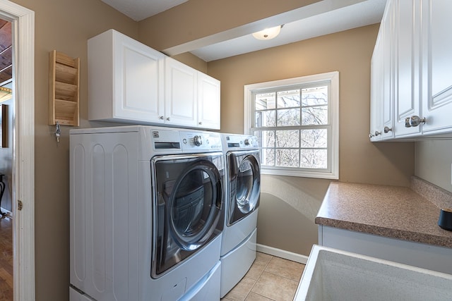 425 Tarheel Dr W, Murphy, NC 28906 - clothes washing area featuring washer and dryer, light tile patterned floors, and cabinet space
