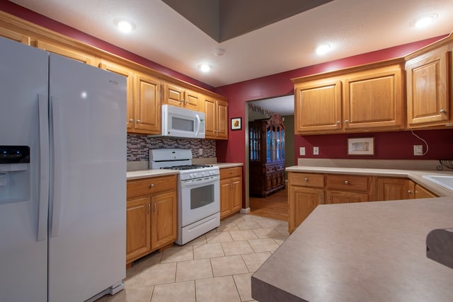 kitchen with decorative backsplash, white appliances, and light tile patterned floors