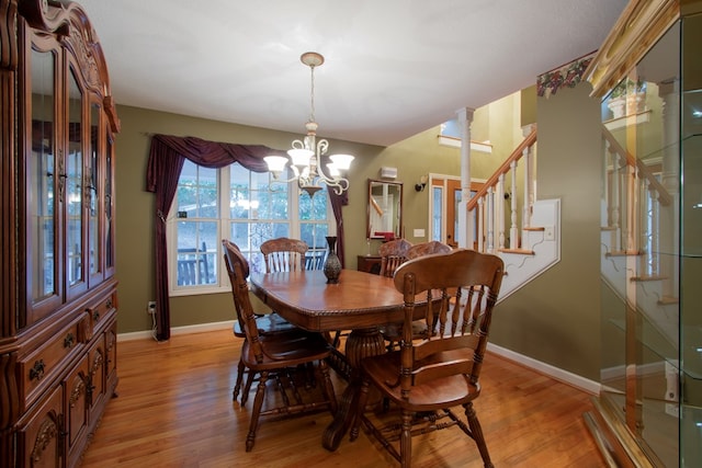 dining area featuring light hardwood / wood-style flooring, ornate columns, and a notable chandelier