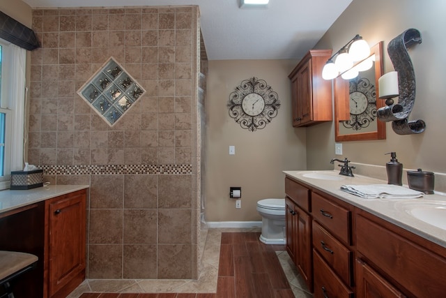 bathroom featuring toilet, vanity, and a shower