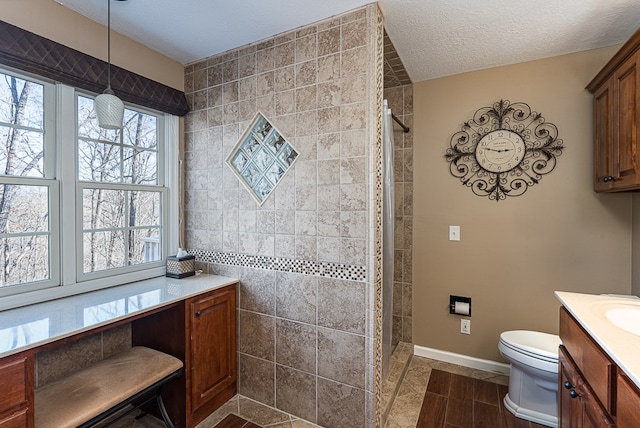 425 Tarheel Dr W, Murphy, NC 28906 - bathroom featuring vanity, baseboards, a textured ceiling, toilet, and a tile shower
