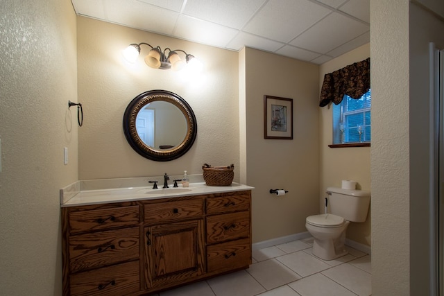 bathroom with toilet, vanity, tile patterned flooring, and a paneled ceiling