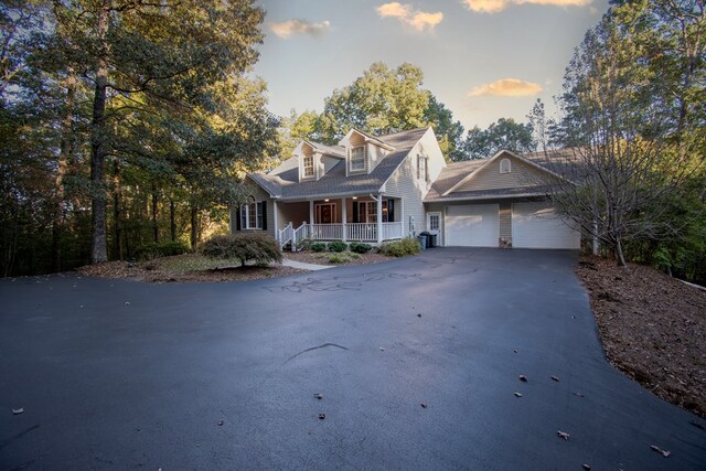 new england style home featuring a garage and covered porch