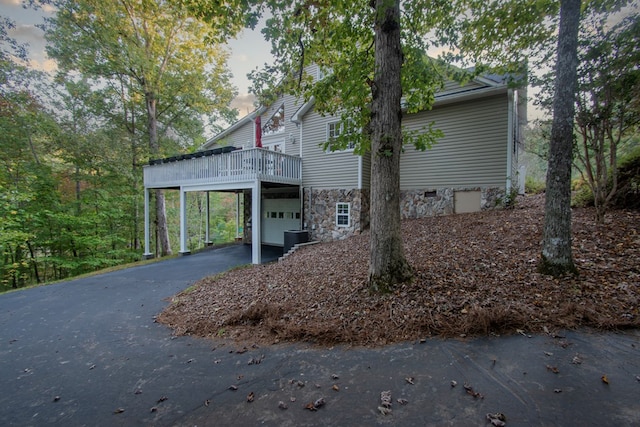 property exterior at dusk featuring a deck, a garage, and central air condition unit