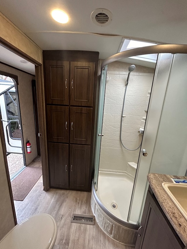 bathroom featuring toilet, vanity, an enclosed shower, and hardwood / wood-style floors