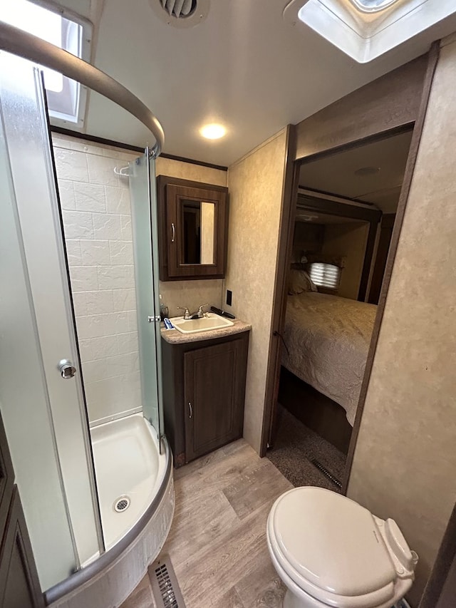 bathroom featuring walk in shower, vanity, hardwood / wood-style flooring, and toilet