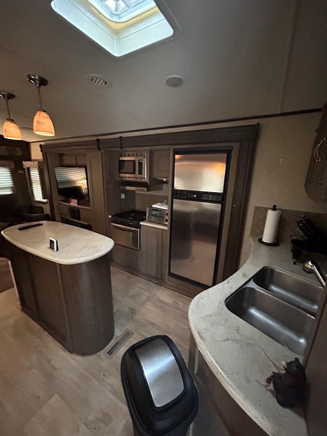 kitchen featuring dark brown cabinets, stainless steel appliances, sink, and a skylight