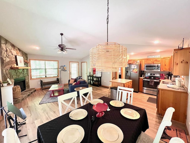 384 Shadow Pines Dr, Murphy, NC 28906 - dining room featuring light wood-type flooring, a ceiling fan, lofted ceiling, and a stone fireplace