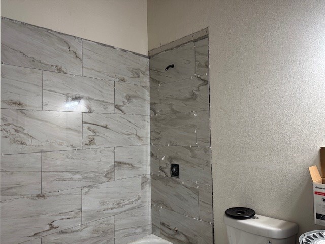 bathroom with tiled shower / bath combo and toilet