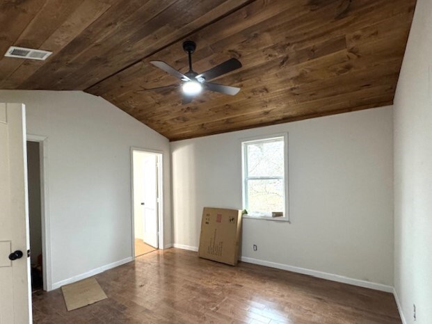 spare room featuring dark hardwood / wood-style floors, ceiling fan, wood ceiling, and vaulted ceiling