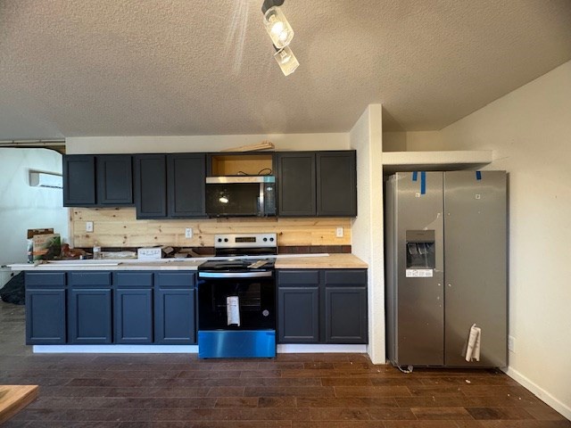 kitchen featuring a textured ceiling, dark hardwood / wood-style floors, backsplash, and stainless steel appliances