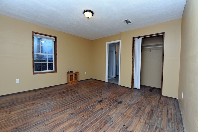 unfurnished bedroom with a closet, dark hardwood / wood-style flooring, and a textured ceiling