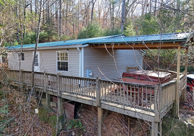 back of house with a hot tub and a deck