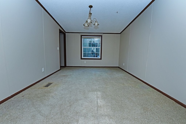 empty room featuring crown molding, a textured ceiling, light carpet, and a chandelier