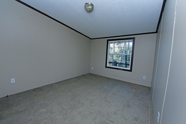 carpeted spare room featuring a textured ceiling, lofted ceiling, and ornamental molding