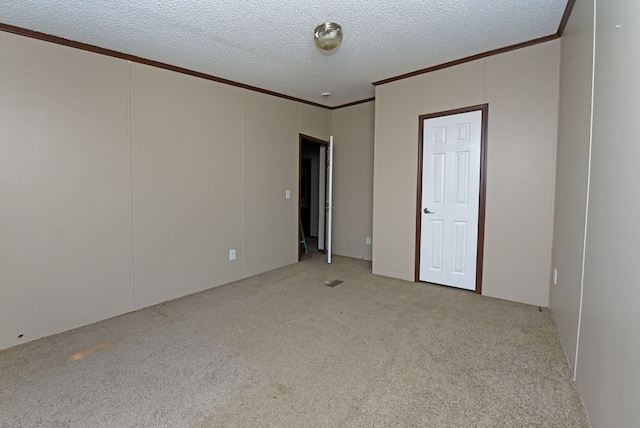 carpeted empty room featuring a textured ceiling and ornamental molding