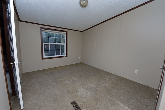 spare room featuring light carpet, a textured ceiling, and ornamental molding