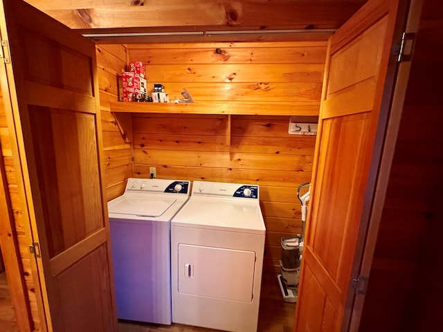 laundry area featuring wooden walls, washing machine and dryer, and laundry area