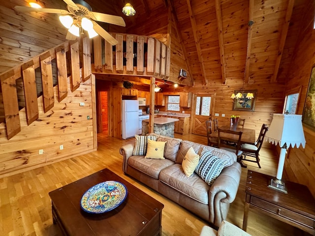 living room with beamed ceiling, light wood-style floors, wood walls, wood ceiling, and ceiling fan