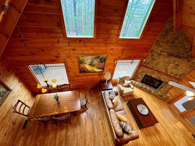 living room with a stone fireplace, wooden walls, and wood-type flooring