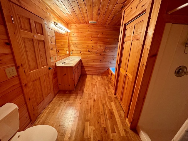 bathroom with wooden walls, toilet, hardwood / wood-style floors, wooden ceiling, and vanity