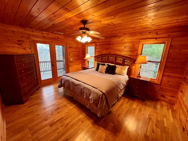 bedroom with hardwood / wood-style floors, access to outside, multiple windows, and french doors