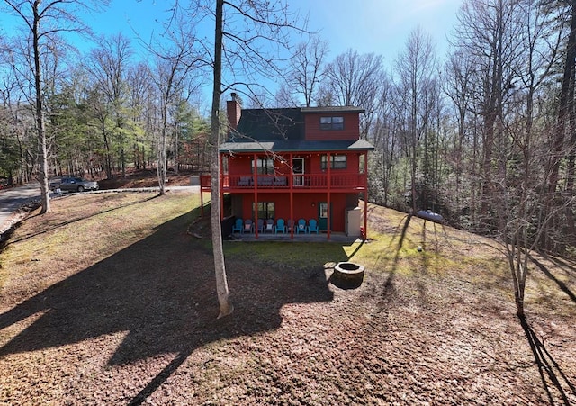 back of house featuring a chimney, a deck, and a yard