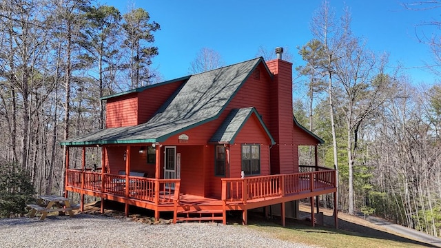 rear view of property featuring roof with shingles and a chimney