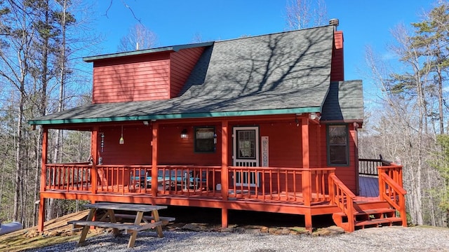 rear view of house featuring a deck, roof with shingles, and a chimney