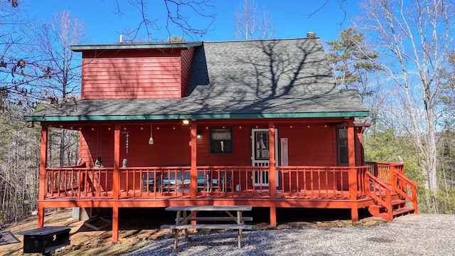 rear view of house featuring a deck and roof with shingles