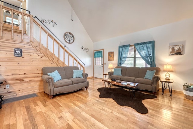 living room featuring stairway, a towering ceiling, and light wood-style floors