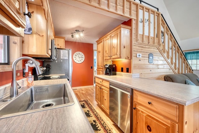 kitchen with a sink, baseboards, light wood-style floors, light countertops, and appliances with stainless steel finishes