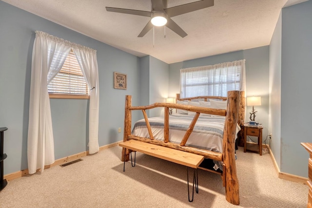 bedroom with light carpet, baseboards, visible vents, ceiling fan, and a textured ceiling