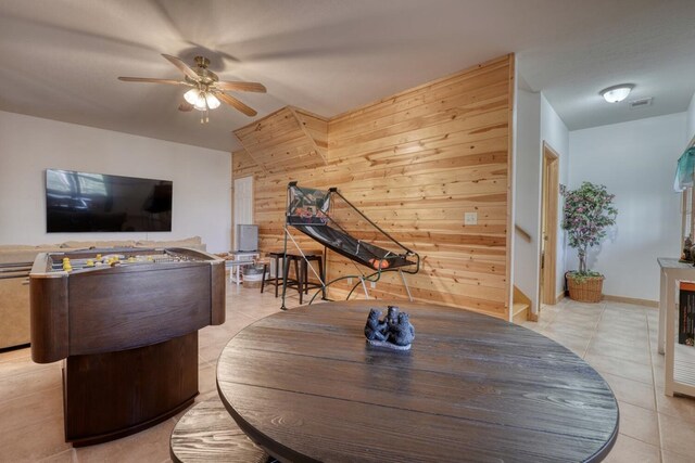 interior space featuring ceiling fan, visible vents, wood walls, and light tile patterned floors