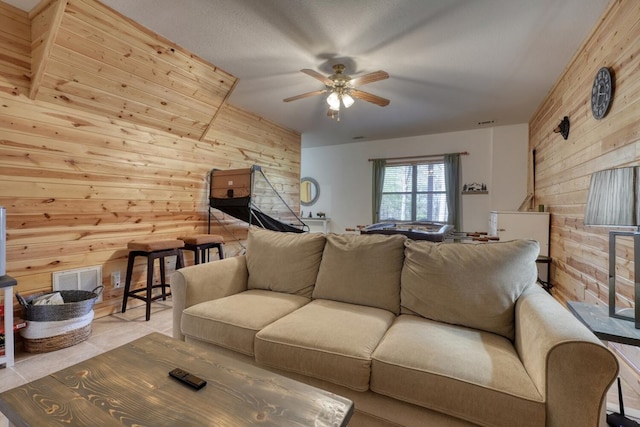 living area with visible vents, ceiling fan, and wooden walls