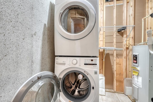 laundry area with water heater and stacked washer / dryer