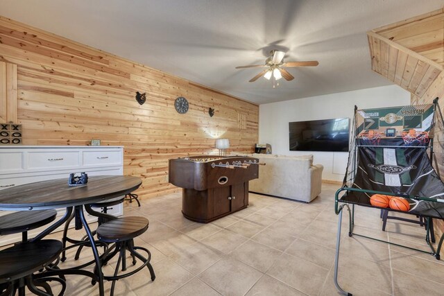 living area with ceiling fan and wood walls
