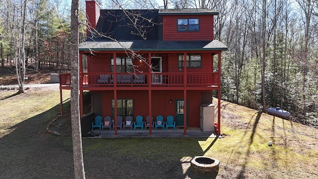 back of property with roof with shingles, a yard, a patio, a chimney, and a deck