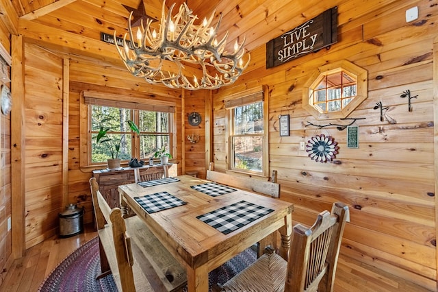 dining area featuring hardwood / wood-style flooring, a chandelier, and wood walls